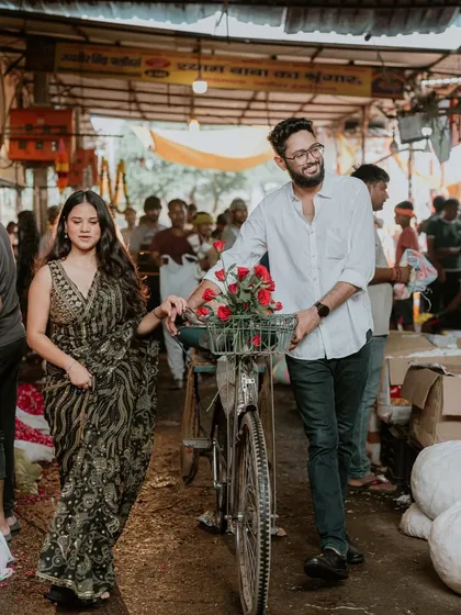 A walking shot through the flower market, with the groom guiding a bicycle filled with roses. This image feels like a scene from a romantic film, set in a real-world location.