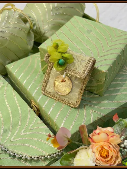 Custom wedding gifts that spark intrigue and charm. This set features gift boxes and matching clutch-style envelopes in a lovely sage green with delicate gold patterns, perfect for presenting 'shagun' or other keepsakes.