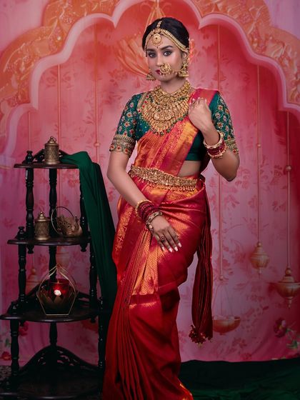 A full-length view of this stunning dusky bride. The red and green Kanjeevaram saree is a classic choice, and the makeup is balanced to complement the rich colors without being overpowering.