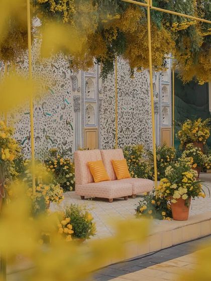 A beautifully framed shot of the Haldi seating, seen through a cascade of yellow flowers.