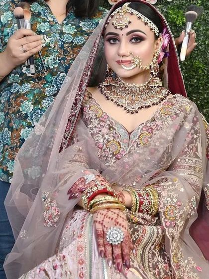 A behind-the-scenes look at a makeup artist getting a model ready in our dusty pink floral lehenga. It shows the complete look coming together.