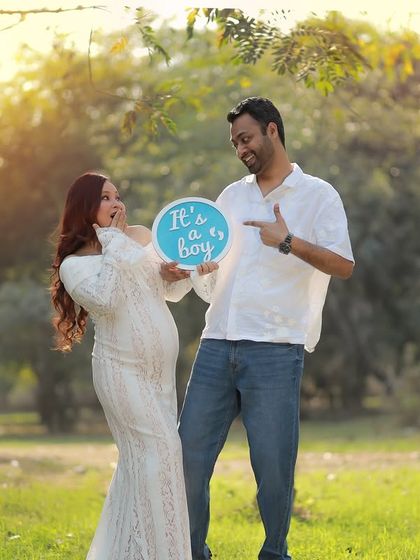 A candid and joyful gender reveal moment. The mother-to-be's surprised and happy expression is perfectly captured in the beautiful outdoor light.