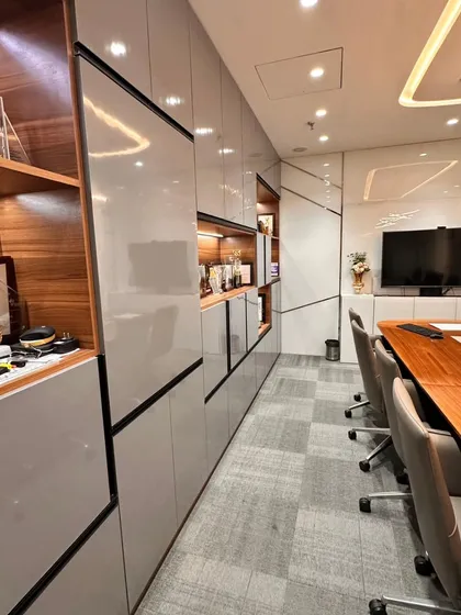 Functionality is built directly into the design. This image shows the seamless integration of storage cabinets with high-gloss finishes, providing ample space to keep the boardroom clutter-free and ready for important meetings.
