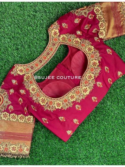 The back of the maroon blouse, showcasing a heart-shaped cutout. The design is heavily embroidered with gold zardozi and red thread, perfect for a bride's special day.