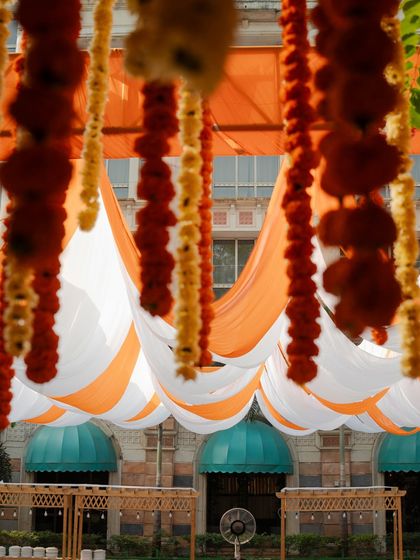 A creative shot looking up through the hanging marigold strings at the draped canopy and the heritage building beyond.