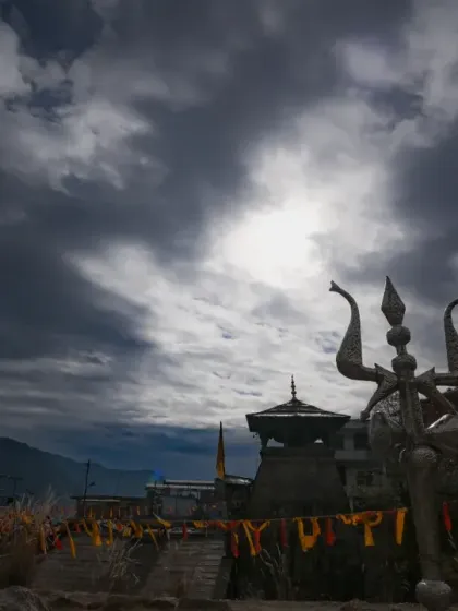A dramatic wide-angle shot of the temple's trishul against a cloudy sky, capturing the powerful and spiritual energy of the location.