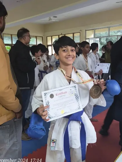 A happy champion with his medal and certificate. The smile says it all. This is the reward for months of disciplined training.