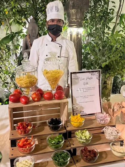 Our live pasta station is always a crowd favorite. Here you can see our chef ready to cook, with a beautiful display of fresh pasta types and a colorful array of toppings like olives, bell peppers, and sun-dried tomatoes for guests to customize their dish.