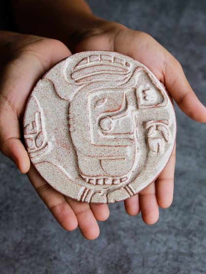 A beautifully finished relief tile of an elephant, held in hand to showcase the detailed carving and texture achieved in the workshop.