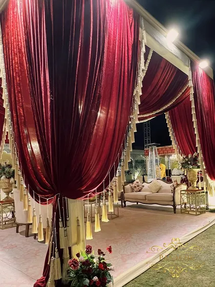 An opulent lounge area created with plush velvet drapes in deep maroon, accented with elegant tassels. This provides a comfortable and regal space for guests to relax and socialize.