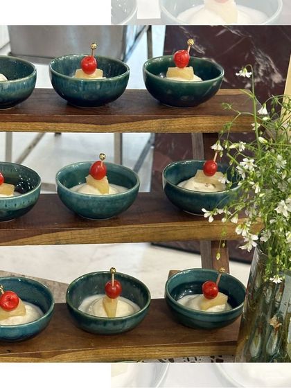 A delightful dessert of pineapple and cherry with cream, served in beautiful teal ceramic bowls. A sweet and simple end to a meal.