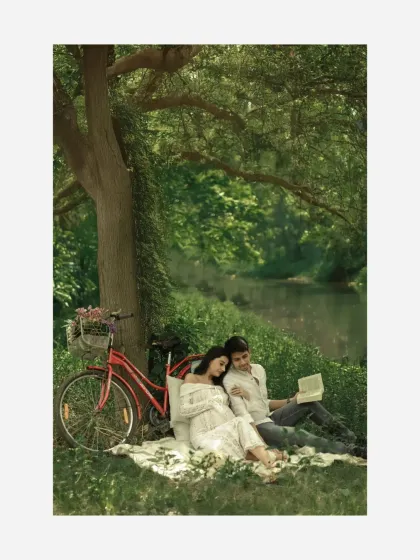 A moment of shared peace. The couple rests together under a tree, reading, in this beautifully styled outdoor session that feels both romantic and serene.