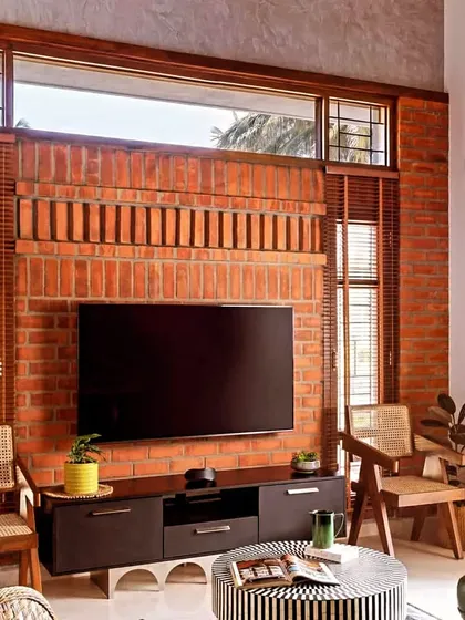 A floor-to-ceiling exposed brick wall serves as the perfect rustic backdrop for a modern TV unit, creating a beautiful contrast of textures.