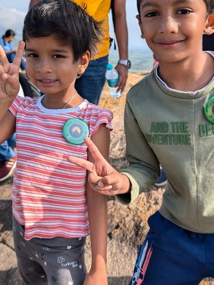 Peace, victory, and a new badge! These young trekkers proudly show off their achievement after a successful hike. Every child earns a badge to remember their adventure.
