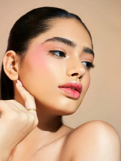 This beauty look features a soft, diffused blush and a glossy lip. The skin has a beautiful, natural-looking sheen that makes the whole look feel fresh and modern.