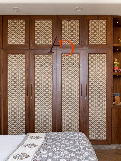 This bedroom features a custom wooden wardrobe with fabric-paneled doors, adding a unique textural element. The design is simple yet stylish, with an integrated bookshelf for added functionality.