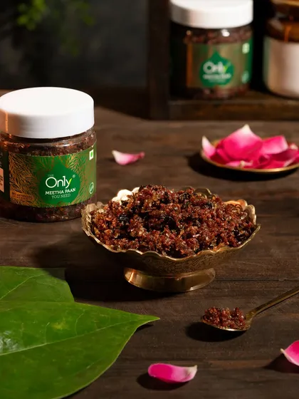 A traditional Meetha Paan mix styled in a brass bowl with betel leaves and rose petals. This composition evokes a sense of authenticity and rich Indian flavor.