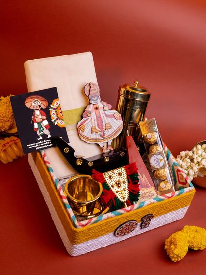 Another angle of the 'Kasavu & Katha' hamper, offering a clear view of the layered items, including the kasavu mundu, Kathakali figurine, and miniature snake boat.