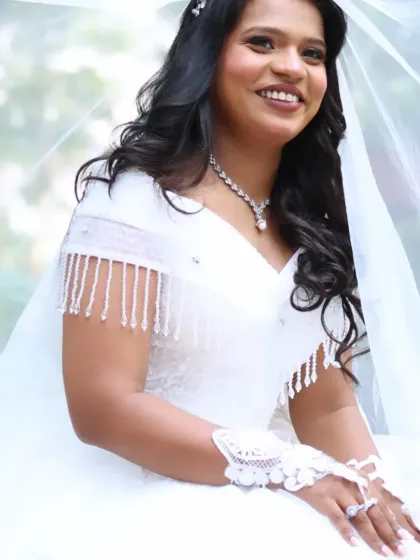The bride is all smiles in her gorgeous white gown. Her hair is styled in soft waves and adorned with a delicate hairpiece, completing her fairytale look.