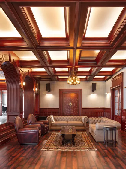 This entertainment lounge in the Wanderlust Villa is inspired by a classic gentleman's club, with rich wood paneling, a coffered ceiling, and comfortable leather seating. It's a moody and atmospheric space perfect for unwinding.