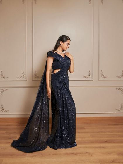 Introducing 'Glamour', a stunning navy blue sequined drape-saree gown. It features a stylish side cutout and a flowing pallu for a modern take on a classic look.