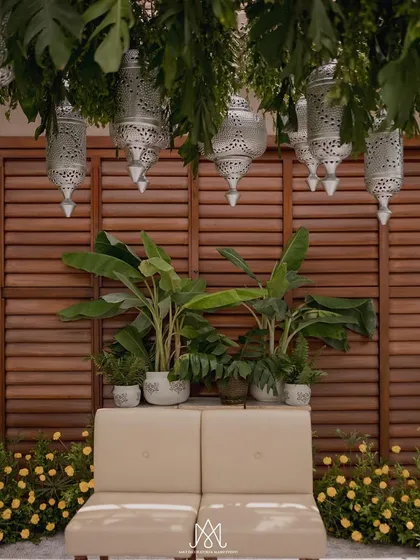 The seating area for the couple, framed by beautiful silver lanterns and lush banana plants, creating a natural and intimate focal point.