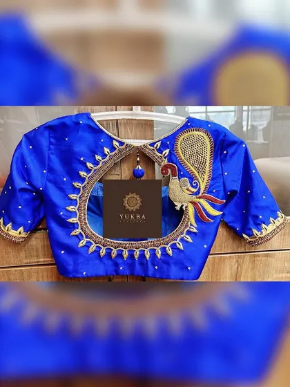 This design is all about making a bold statement. A majestic peacock motif, crafted with zardosi and resham embroidery, becomes the centerpiece of this royal blue blouse, framing an elegant circular back cutout.