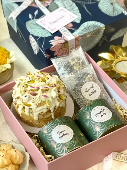 My Diwali hamper is a mix of modern and traditional flavors. It includes a beautiful pistachio-topped tea cake, almond brittle, and savory masala nuts and cumin cookies.
