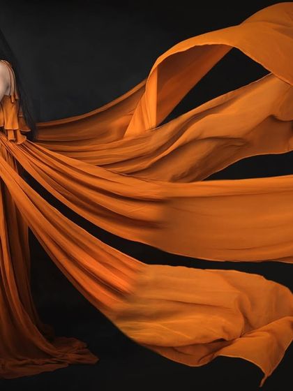 This studio shot showcases the incredible spread of our mustard four-trail gown against a black background, highlighting the color and dramatic flow of the fabric.
