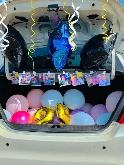 A bright, daytime car trunk surprise. This decoration uses a simple and clean arrangement of balloons, a "Happy Birthday" star balloon, and a string of personal photos, showing that these setups look great any time of day.
