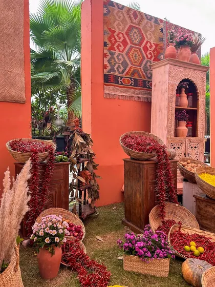 A corner of the bazaar, where baskets overflow with red chilies and spices, set against terracotta walls and a hanging kilim rug. Every detail is curated for authenticity.
