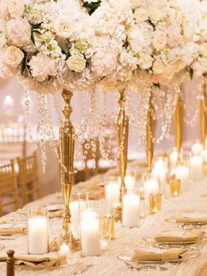 A vision in white and gold. This opulent wedding tablescape features towering floral arrangements with cascading crystals, creating a feeling of pure romance and luxury for a sit down dinner.