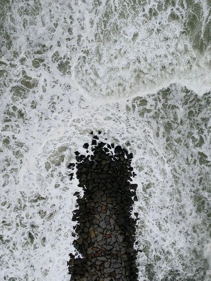 A top-down view of the waves crashing against the tetrapods that protect the highway at Maravanthe.