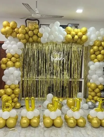 A grand gold and white balloon decoration for a home party, with lettered balloon bases.