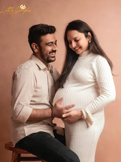 A joyful interaction between the parents-to-be, highlighting their excitement and love in a clean and simple studio setting.