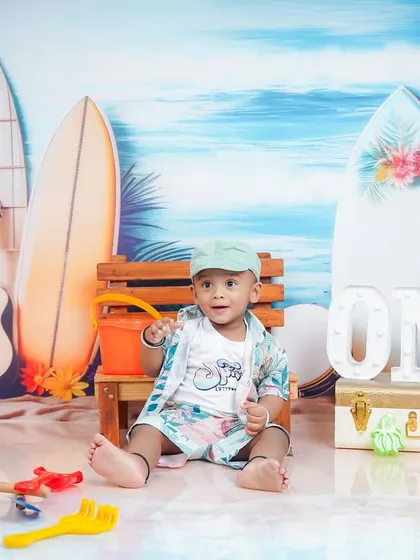 A beach-themed first birthday shoot. The combination of the "ONE" sign and the tropical backdrop makes for a unique milestone photo.
