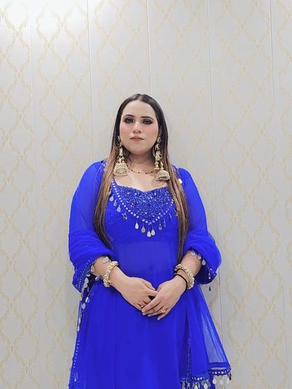 A full-length view of the custom royal blue suit. The Anarkali-style kurta is paired with a matching dupatta adorned with mirror-work tassels, creating a cohesive and striking look.