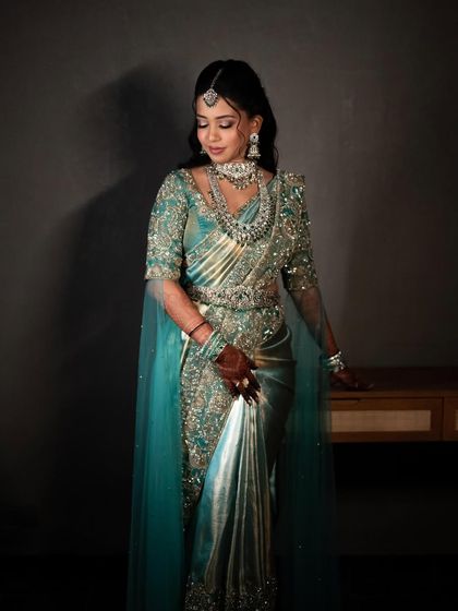 Another shot of the bride in her turquoise saree gown, showing the beautiful drape and the modern, stylish silhouette.