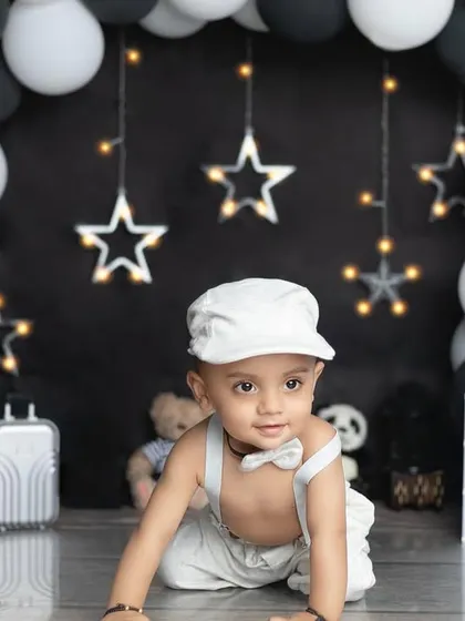 A cute crawling pose from our little man in his all-white outfit, contrasting beautifully with the dark backdrop.