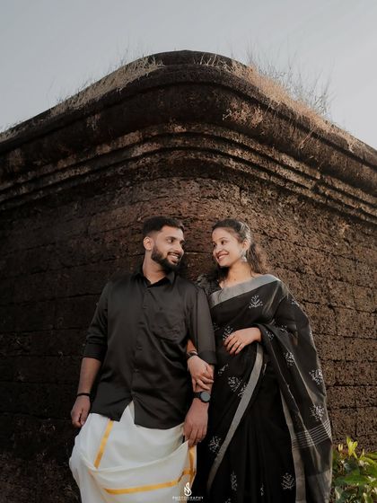 A loving gaze shared between the couple. The man's white mundu and the woman's black saree create a striking and elegant contrast.