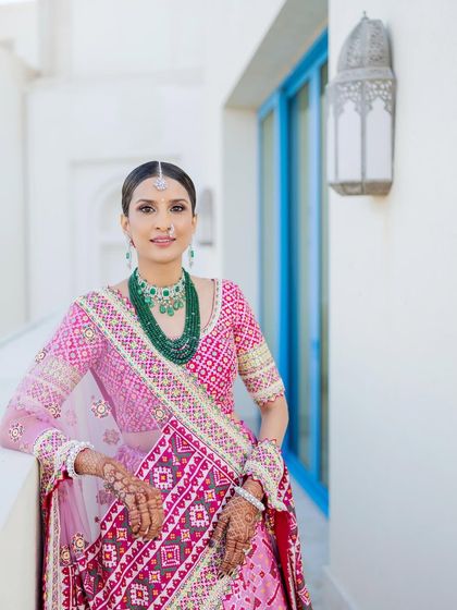 A portrait showcasing the details of this beautiful look. The skin is luminous, the eyes are softly defined, and a classic red bindi completes the traditional aesthetic.