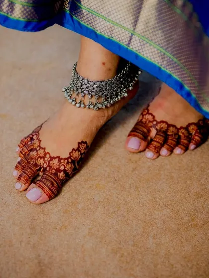 A close-up of the bride's feet, showing the delicate and intricate mehendi design on her toes.