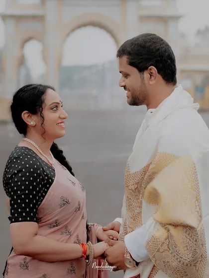 A classic pre-wedding photo with a couple holding hands in front of a majestic archway in Mysore.