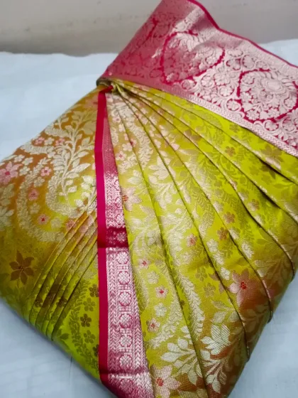 A vibrant lime green Banarasi with a pink border. The pleats are set to showcase the rich brocade work, making it ready for any festive occasion.