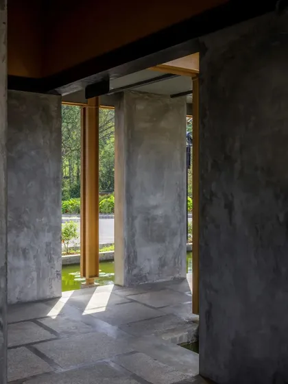 Sunlight streams into a corridor at Teyla, highlighting the texture of the micro-concrete walls and the stone flooring, with a view of the water channel outside.