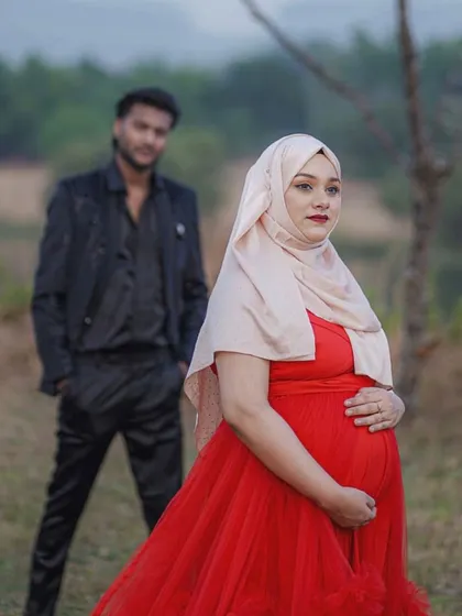 This shot captures the strength and beauty of the mom-to-be, with her partner looking on. The red infinity gown provides a classic silhouette that is both comfortable and elegant for a maternity photo session.