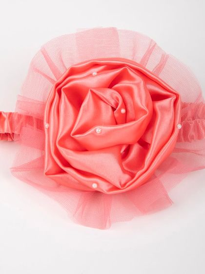 A close-up of the coral satin rose headband with pearl details.