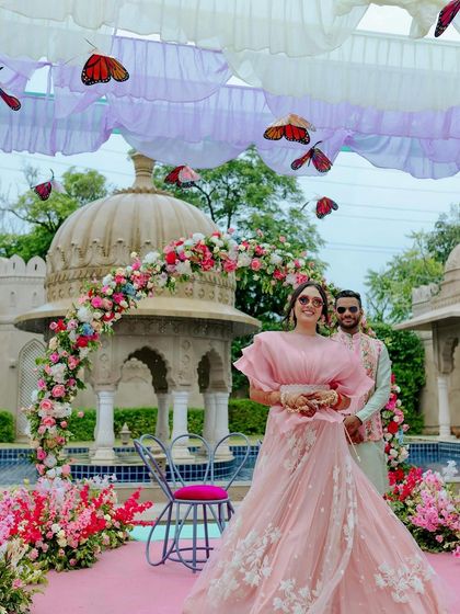The bride shines at her whimsical Mehendi, with fluttering butterflies suspended from the ceiling and a backdrop of historic architecture.