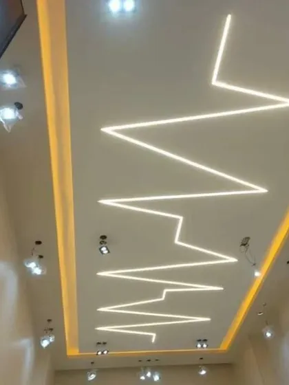 This design uses profile lighting to create a dramatic zigzag or heartbeat pattern across the ceiling. It's a bold and artistic statement for any modern space.