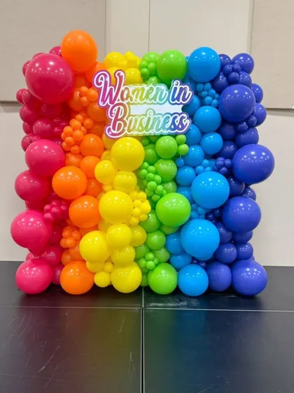 For a 'Women in Business' conference, we designed this vibrant rainbow balloon wall with a custom branded sign. This backdrop served as a powerful visual centerpiece and a popular spot for photos.